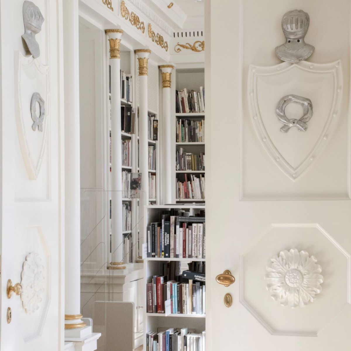 Fotografia do wydarzenia przedstawia białe drzwi ozdobione między innymi rzeźbioną rozetą, nałęczką z herbu rodu Raczyńskich i hełmem rycerskim. Jedno skrzydło drzwi jest otwarte, za nim jasne wnętrze z kolumnami i książkami.