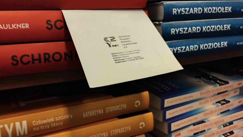Stos książek z kartką z pieczęcią Narodowego Programu Rozwoju Czytelnictwa 2.0