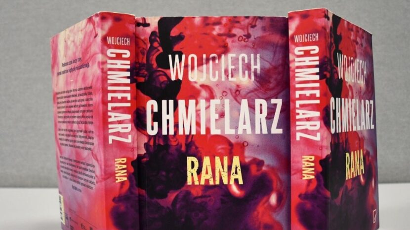 Obrazek do wydarzenia, kilka książek z okładką w tonacji czerwono-różowej, kształt przypomina rozpuszczający się barwnik w wodzie.