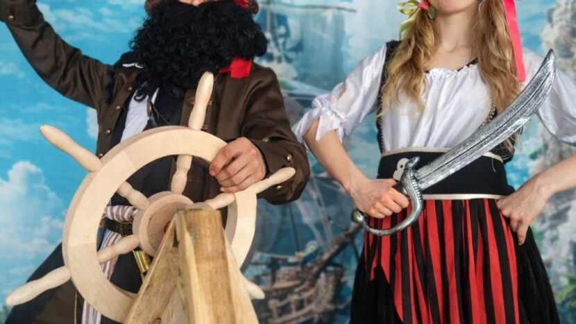Obrazek do wydarzenia, dwoje ludzi, kobieta i mężczyzna, przebranych za piratów przy sterze.