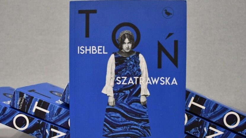Obrazek do wydarzenia, niebieska okładka książki z fotografią kobiety. Niebieska sukienka ma motyw wodnych fal, rękawy charakter rustykalny, kobieta ma chustkę na głowie, stoi zgarbiona i patrzy spode łba.